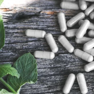 kratom capsules laying next to leaves